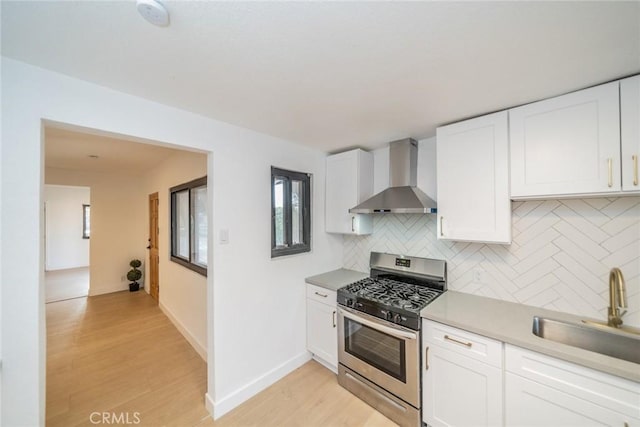 932 S Bon View Ave, Ontario, CA 91761 - kitchen featuring wall chimney exhaust hood, stainless steel range with gas cooktop, light wood-style flooring, tasteful backsplash, and white cabinets
