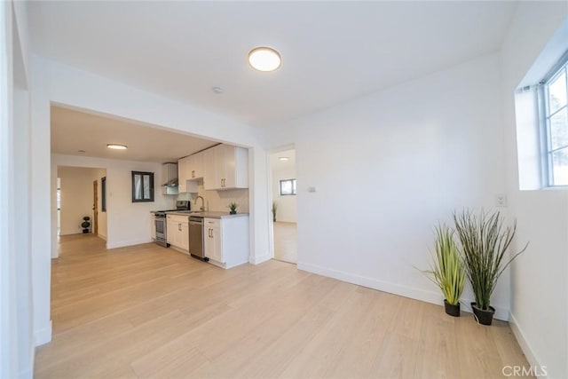 932 S Bon View Ave, Ontario, CA 91761 - kitchen with stainless steel appliances, light wood finished floors, white cabinets, light countertops, and wall chimney exhaust hood