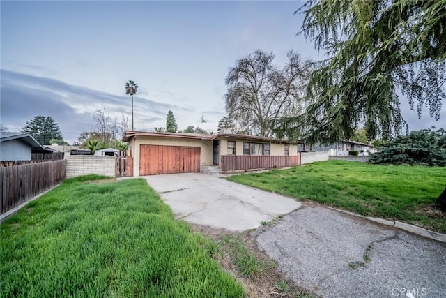 view of front of home with fence, a front yard, stucco siding, an attached garage, and driveway