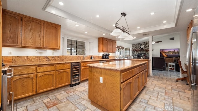 18668 Lemert St, Hesperia, CA 92345 - kitchen featuring ceiling fan, a tray ceiling, stone tile floors, a center island, and wine cooler