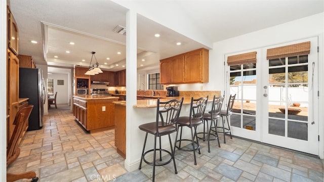 18668 Lemert St, Hesperia, CA 92345 - kitchen featuring stone tile flooring, a peninsula, under cabinet range hood, stainless steel appliances, and french doors