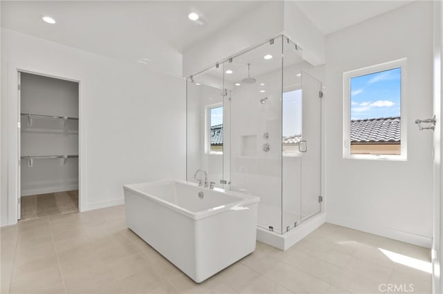bathroom with a shower stall, a soaking tub, tile patterned flooring, and baseboards