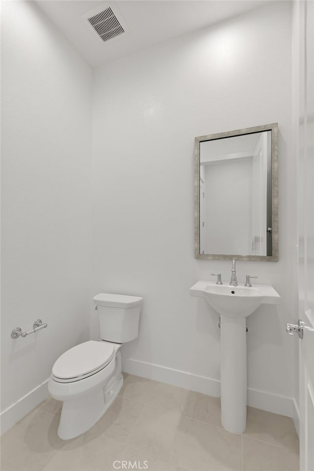 half bath with baseboards, toilet, and visible vents