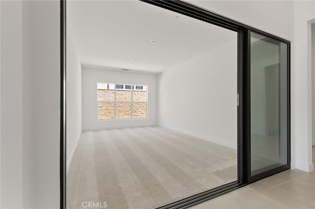 interior space featuring light colored carpet and baseboards