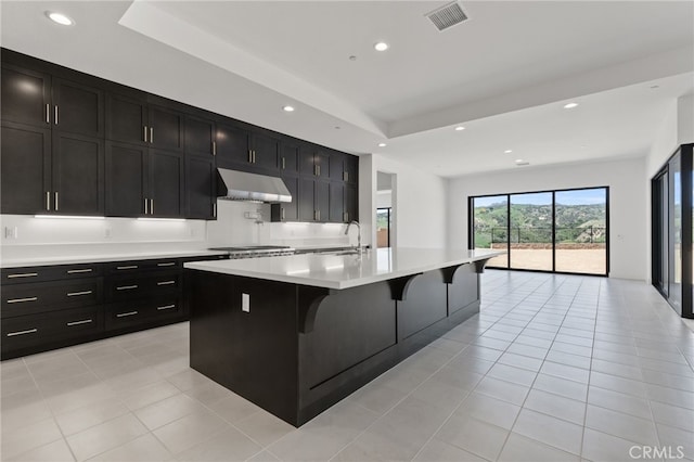 kitchen featuring recessed lighting, dark cabinetry, visible vents, and under cabinet range hood