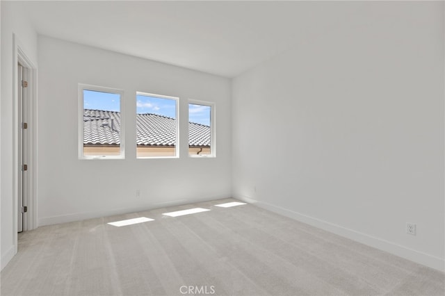 empty room with baseboards and light carpet