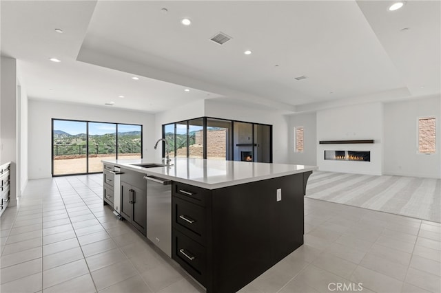 kitchen featuring a sink, open floor plan, recessed lighting, dark cabinets, and a raised ceiling