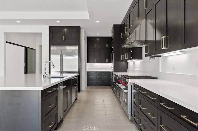 kitchen featuring recessed lighting, high quality appliances, a sink, and light countertops