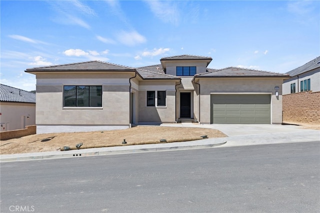 prairie-style house featuring a garage, a tile roof, driveway, and stucco siding