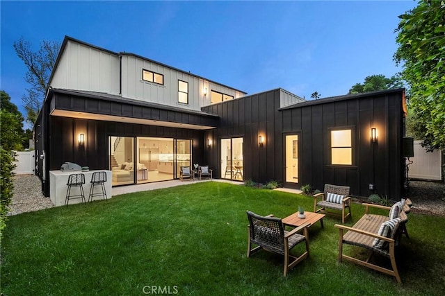 rear view of house featuring board and batten siding, a yard, a standing seam roof, and metal roof