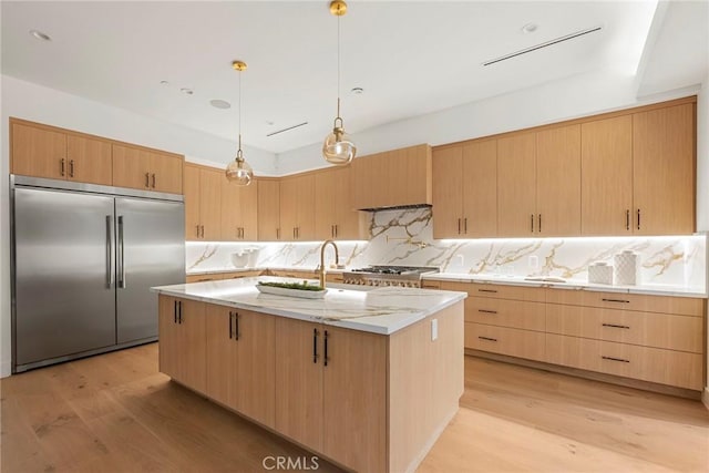 kitchen with built in fridge, light brown cabinets, and light wood finished floors
