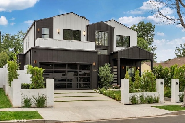 contemporary home featuring a balcony, an attached garage, fence, concrete driveway, and board and batten siding