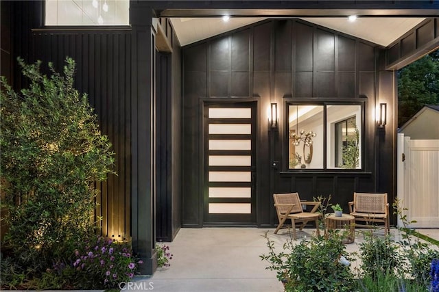 property entrance with board and batten siding and fence