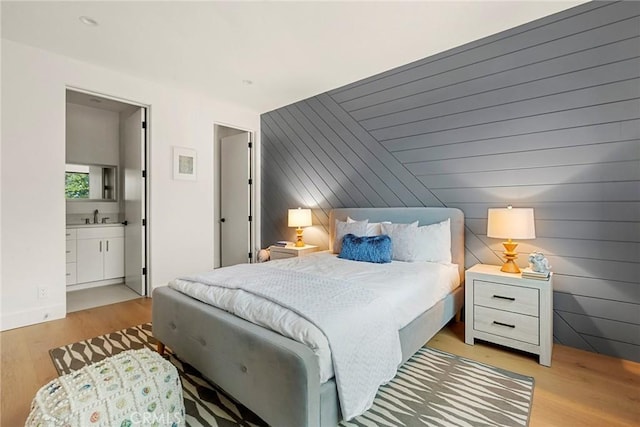 bedroom featuring light wood-style floors, a sink, and connected bathroom