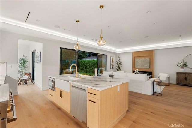 kitchen featuring a sink, light brown cabinets, stainless steel appliances, and light wood-style flooring