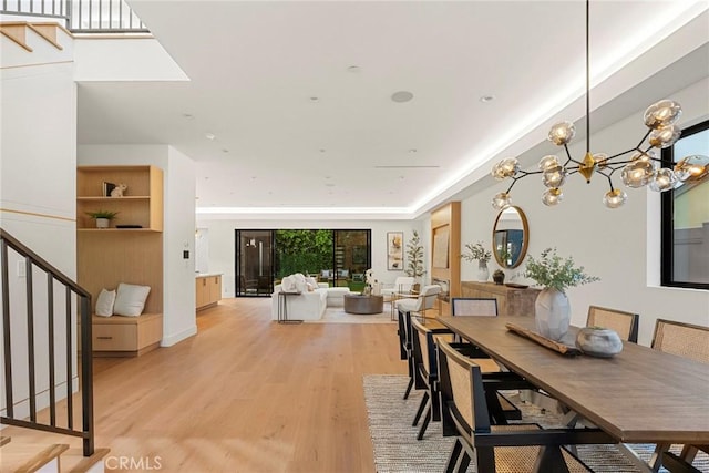 dining room featuring stairs, light wood-type flooring, and a chandelier