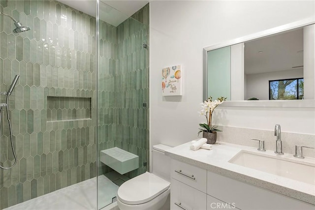 bathroom with a shower stall, toilet, and vanity