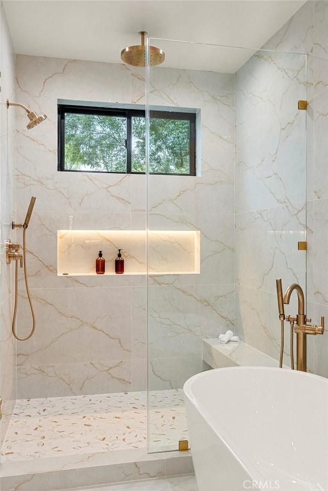 bathroom featuring healthy amount of natural light, a marble finish shower, a freestanding bath, and tile walls