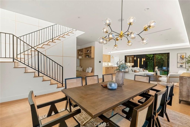 dining room featuring stairway, light wood-style floors, a chandelier, and baseboards