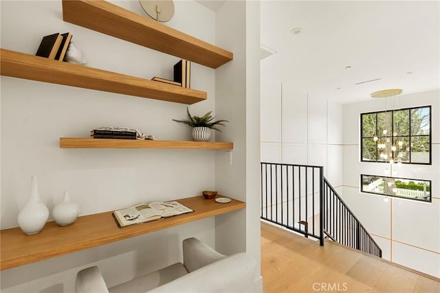 corridor featuring an upstairs landing, light wood-style flooring, and a chandelier
