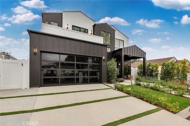 contemporary home featuring board and batten siding, fence, a balcony, and concrete driveway