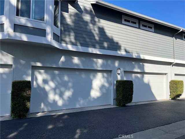 view of side of home with a garage and stucco siding
