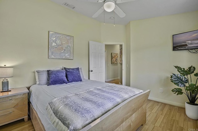 bedroom featuring baseboards, a ceiling fan, visible vents, and light wood-style floors