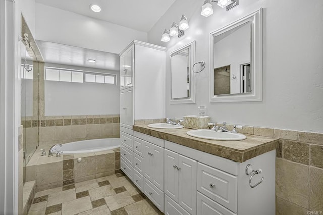 bathroom with double vanity, a garden tub, and a sink