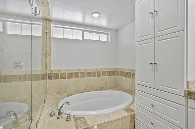 bathroom with a garden tub and tiled shower