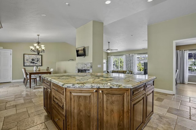 kitchen featuring recessed lighting, stone tile flooring, baseboards, and ceiling fan with notable chandelier