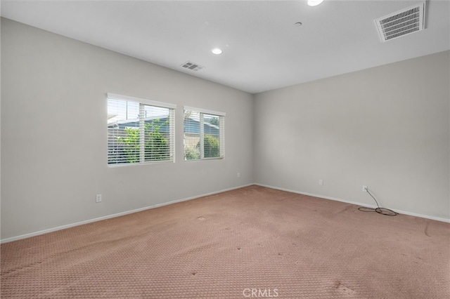 empty room with visible vents, baseboards, and light carpet