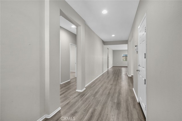 corridor with wood finished floors, baseboards, and recessed lighting
