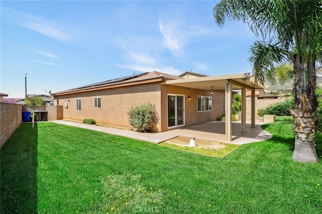 rear view of house featuring solar panels, a patio area, a yard, a fenced backyard, and stucco siding