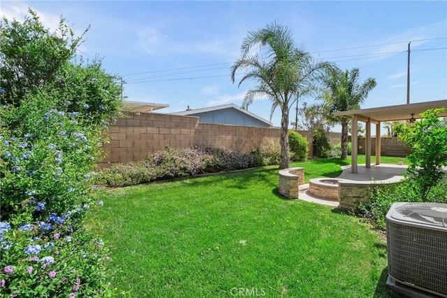 view of yard with central air condition unit, a fenced backyard, a fire pit, and a patio area