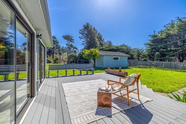 wooden terrace with a lawn, an outbuilding, and fence