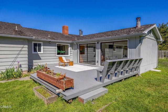 rear view of house with a lawn, a chimney, and a deck