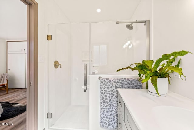 bathroom with wood finished floors, a stall shower, recessed lighting, and vanity