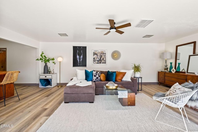 living room featuring visible vents, light wood-style floors, and ceiling fan