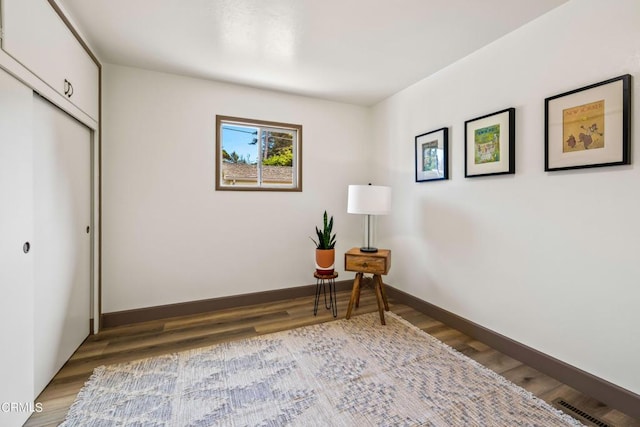 sitting room with baseboards and wood finished floors