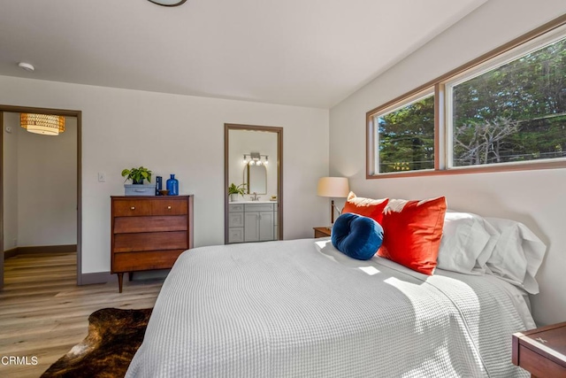 bedroom featuring connected bathroom, light wood-style floors, and baseboards
