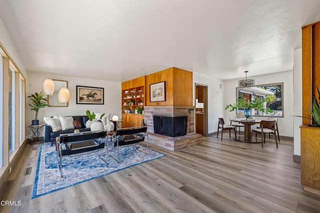 living room featuring baseboards, a fireplace, visible vents, and wood finished floors