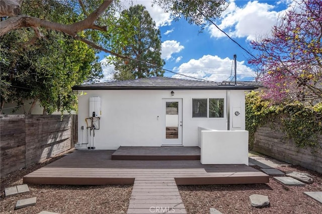 exterior space with stucco siding, a deck, and fence