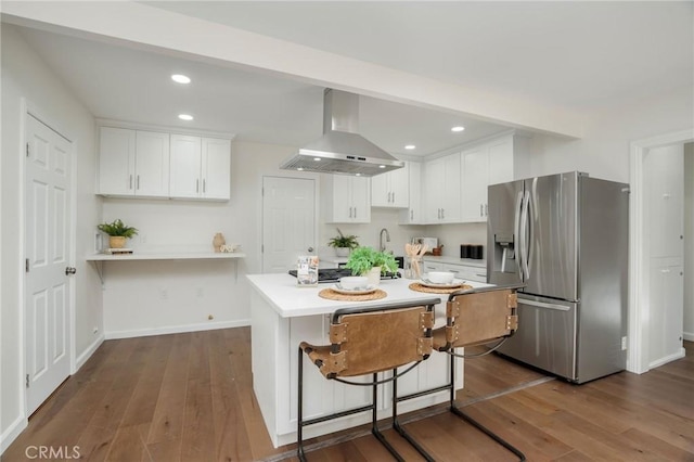 kitchen with wall chimney exhaust hood, white cabinetry, stainless steel appliances, and dark wood-style flooring
