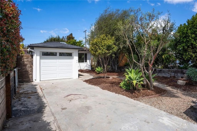view of front of home with stucco siding, fence, a garage, and concrete driveway