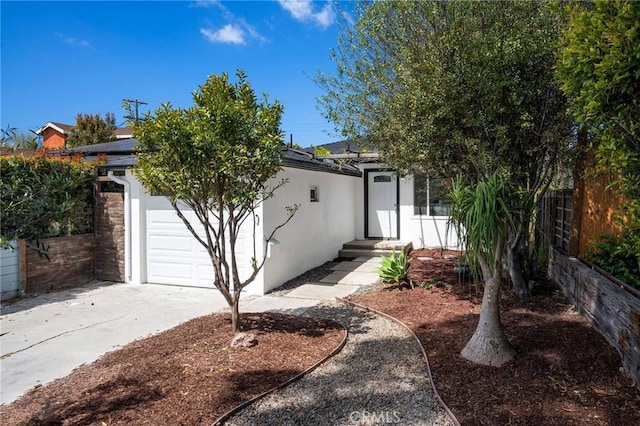 view of front of property with stucco siding, driveway, a garage, and fence