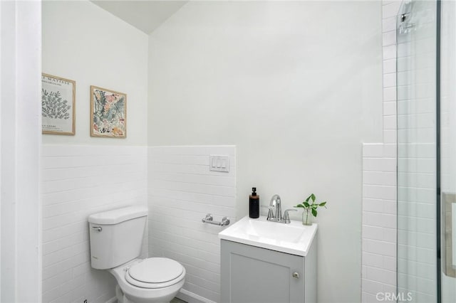 bathroom featuring toilet, a wainscoted wall, tile walls, and vanity