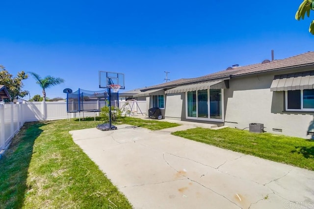 exterior space with stucco siding, a patio, a fenced backyard, and a trampoline
