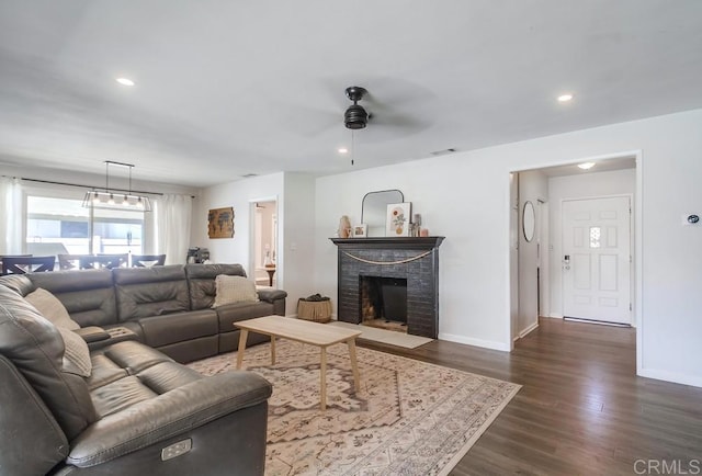 living area featuring a ceiling fan, dark wood finished floors, baseboards, a brick fireplace, and recessed lighting