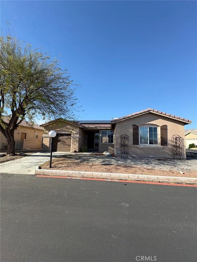 65565 Acoma Ave Unit 68, Desert Hot Springs, CA 92240 - view of front of house featuring a tiled roof, roof mounted solar panels, a garage, stucco siding, and concrete driveway