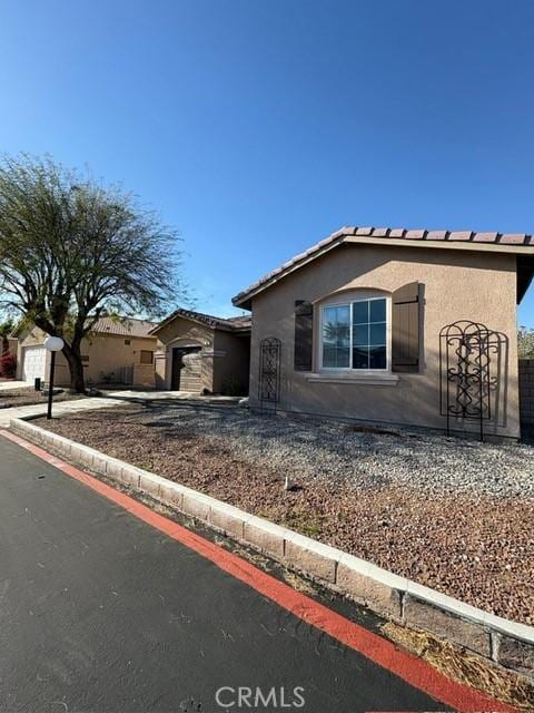 65565 Acoma Ave Unit 68, Desert Hot Springs, CA 92240 - view of front of home featuring driveway, stucco siding, an attached garage, and a tile roof